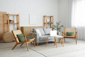 Beautiful interior of living room with grey sofa, armchairs, coffee table, shelving units and olive tree
