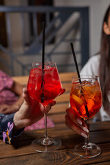 Two friends lifting cocktails in a lively bar scene, expressing joy and celebration