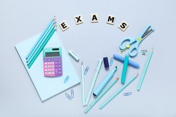 Frame made of different stationery and word EXAMS on grey background