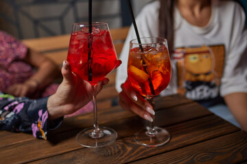 Two friends lifting cocktails in a lively bar scene, expressing joy and celebration