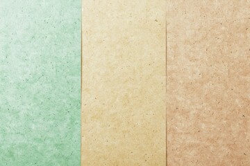 Fototapeta premium Three pieces of recycled paper are laying side by side creating an abstract background with neutral green, beige and brown colors