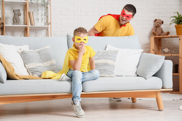 Little boy with his father in superhero costumes playing at home