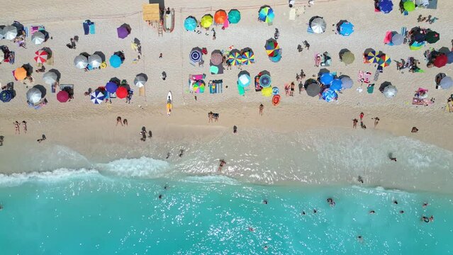 An aerial view of Porto Katsiki Beach in Greece, showcasing the white sand, turquoise water, and colorful umbrellas dotting the shore.