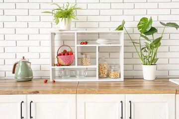 Wicker basket with tasty strawberries on shelves in kitchen