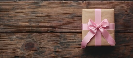 Fototapeta premium Gift box with pink ribbon on wooden table