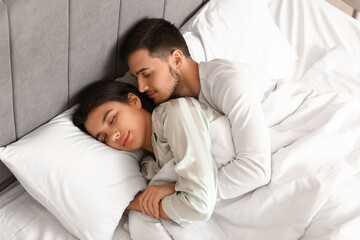 Young woman with her husband lying in bedroom