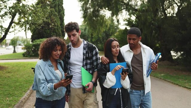 Diverse students using smartphone in park, enjoying outdoor time and learning together. Multicultural students strolling in park, engrossed in smartphone