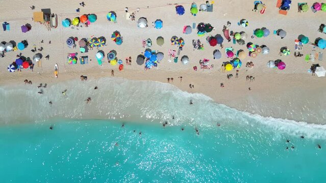 An aerial photograph showcasing the iconic Porto Katsiki beach in Greece. Captures the pristine white sand, turquoise waters, and colorful umbrellas lining the shore. Pull up movement
