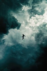 Fototapeta premium Silhouette of a man flying in the stormy cloudy sky.
