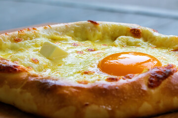 Adjarian khachapuri - traditional Georgian cuisine close up. Ready-to-eat baking with cheese, butter and egg