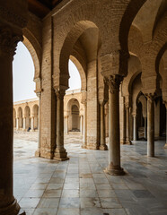 Fototapeta premium Corridor gallery around inner courtyard of Great Mosque of Kairouan in Tunisia with traditional Islamic arches and columns decorated with Corinthian capitals