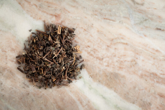 A pile of Dry Organic Bhringraj (Eclipta prostrata) leaves, on a marble background. Top view