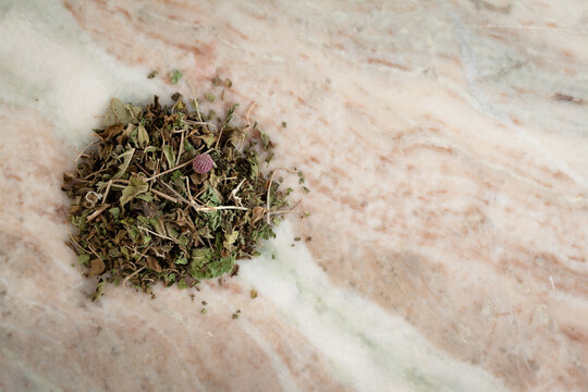 A pile of Dry Organic Gymnema or Gurmar (Gymnema sylvestre) leaves, on a marble background. Top view
