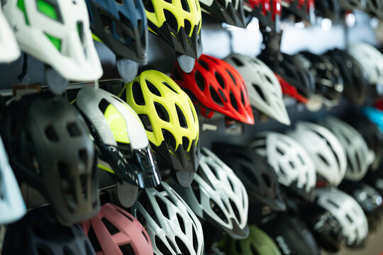 Variety of bicycle helmets in different colors and designs neatly displayed on shelves in specialized bike shop