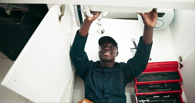 Black man, plumbing and pipe with repair for leak, sink or fix in maintenance or service at home. Young African, male person or plumber working on faucet, basin or water leakage in kitchen at house
