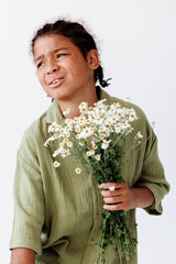 Innocent joy young boy holding a bunch of daisies against a clean white background