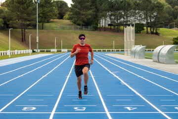 Male Runner with Sunglasses Sprinting towards Camera on Blue Athletic Track