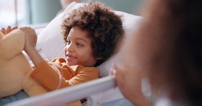 Boy, hospital and teddy bear in bed with smile, recovery and help for patient with mom on bedside for support. Treatment, iv drip and hand for healthcare, toy and rehabilitation in pediatric care