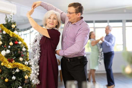 Middle-aged man and elderly woman are dancing contemporary discofox in couple during lesson at studio in New Year atmosphere. Leisure activities and hobby for positive people.