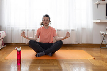 Beautiful woman practicing yoga at home on yoga mat meditating relaxed. Well being, wellness...