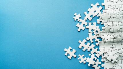 Fragment of a folded white puzzle and a pile of unkempt puzzle pieces on a blue surface background with copy space.
