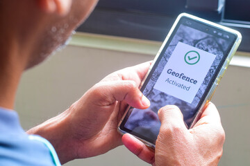 Man gets a successful geofence activation message on his smartphone. Virtual perimeter settings for location tracking system using real-time approach, concepts.	
