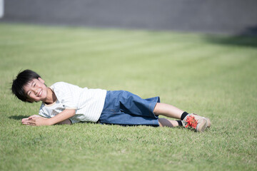  芝生に寝転がる笑顔の男の子のカメラ目線