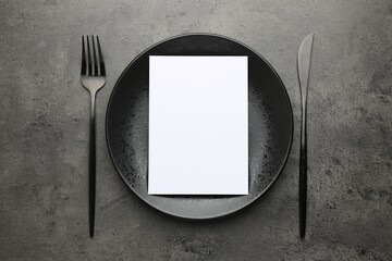 Empty menu, plate and cutlery on grey table, top view. Mockup for design