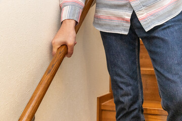 手すりを握りながら階段を下りる人物