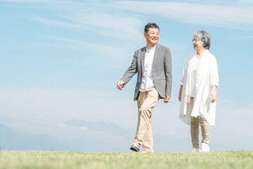 公園・旅行先を話しながら歩く高齢者夫婦（シニア・男女）  © buritora