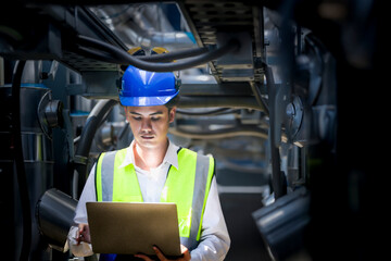 An industrial worker in high-visibility gear and a blue helmet meticulously examines the intricate...