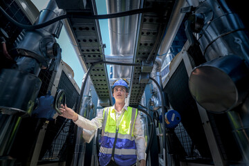 A technician in a bright safety vest and helmet conducts a thorough inspection of complex industrial equipment. The scene highlights the importance of precision and safety in engineering tasks.