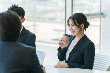 オフィスの休憩スペースで談笑するビジネスマン男女
