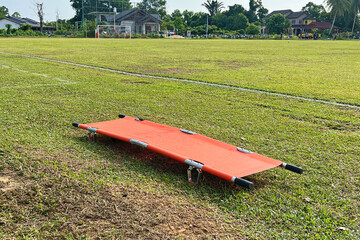 orang stretcher on the field ready to be use if accident happen in the game.