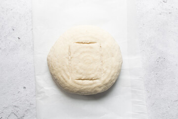 Overhead view of sourdough bread dough about to be baked, artisan bread dough on parchment lined baking tray, process of making homemade bread