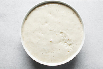 Overhead view of nigerian puff-puff dough that has proofed, puff-puff dough in a white mixing bowl, process of making puff-puff or bofrot