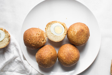 Overhead view of homemade nigerian egg roll, freshly made african egg roll on a white plate, flatlay of egg wrapped in fried dough