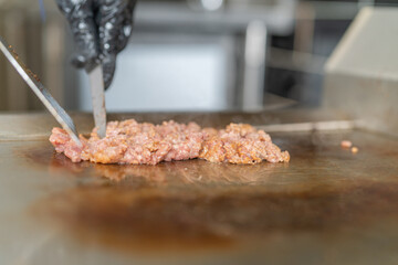 Cooking ground beef on the griddle in the restaurant