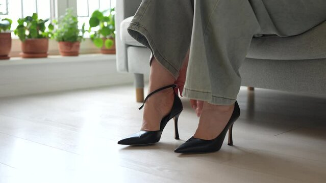 Woman takes off shoes after walk, discovering severe calluses on feet from using heels. Painfully worn feet from uncomfortable and narrow shoes. Exhausted female feeling feet discomfort, pain, ache. 