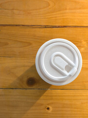 Paper cup with lid on wooden background (Top view)