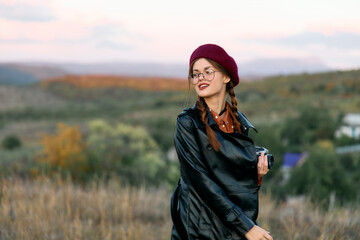 Stylish woman in red beret and leather jacket poses confidently in the middle of a vast field