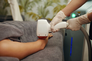 Cosmetologist removing hair from body of client with laser