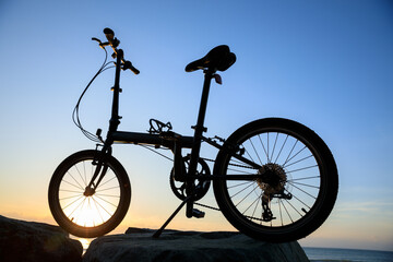 A folding bike on sunrise seaside rock