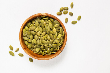 Pumpkin seeds in a wooden bowl, view from the top
