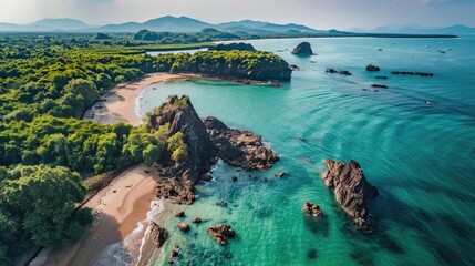 Aerial view of a stunning coastal landscape with rocky formations, turquoise water, and lush greenery under a clear sky.