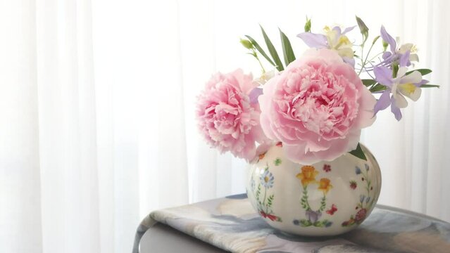 Bouquet of peonies and wild flowers in vase on table near window from private flowerbed. Florist and composition. Nature and beauty in house in summer. 