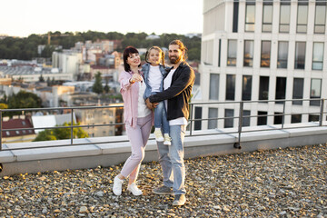 Happy family celebrating new house key on rooftop terrace in urban setting. Smiling parents with child enjoying momentous occasion.