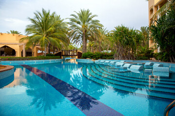 Swimming pool with clear water surrounded by palm trees in one of the best resorts