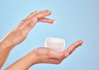 Woman, hands and cream jar in studio for skincare, sunscreen and cosmetics on blue background. Female person, body care and moisturizer pot for hydrated skin, treatment and container for dermatology