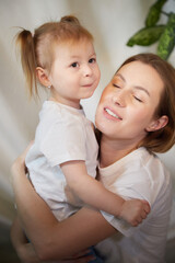 Happy loving family. Mother and her daughter child girl playing and hugging in living room with wicker chair